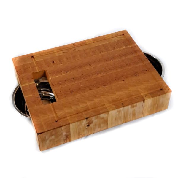 Raised Cherry hardwood end grain cutting board prep station with built-in waste cutout and 2 stainless steel bowls on a track beneath.