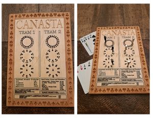 Handcrafted wooden board game featuring a Canasta scorecard with storage box for accessories. Next to it a Canasta wood score card with metal pegs and playing cards displayed.