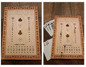 Handcrafted wooden board game featuring a Euchre scorecard with storage box for accessories. Next to it a Euchre wood score card with metal pegs and playing cards displayed.