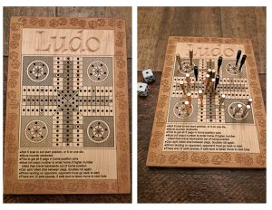 Handcrafted wooden board game featuring a Ludo scorecard with storage box for accessories. Next to it a Ludo wood score card with metal pegs and dice displayed.