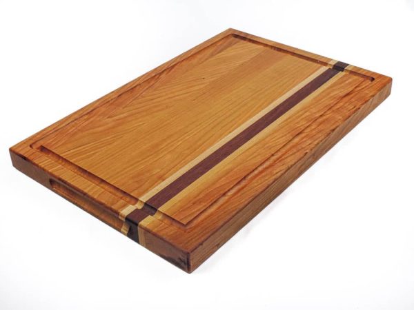 Cherry edge grain cutting board with maple and purple heart accent strips showcasing juice groove and handles. Made in Canada by Bergeron Woodgrains