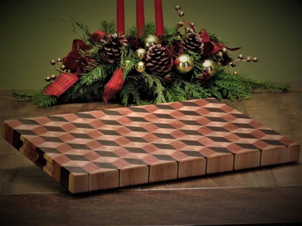 Handcrafted 12x18" 3D tumbling block end grain cutting board resting slightly elevated on a harvest table made by Bergeron Woodgrains