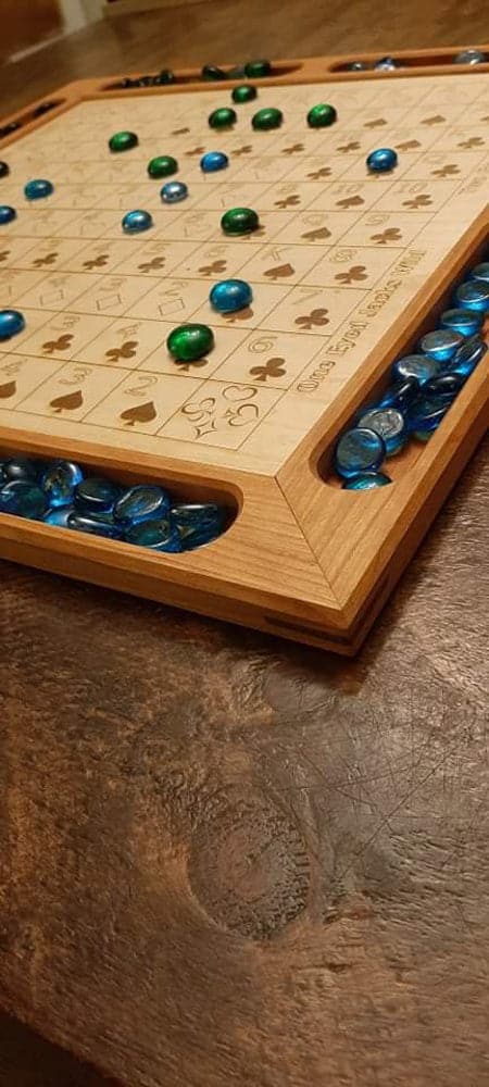 Handcrafted wood sequence board game featuring a cherry border with game piece cutouts and laser engraved baltic birch centre. Canadian made by Bergeron Bergeron