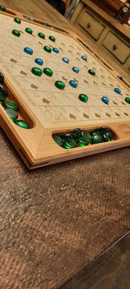 Handcrafted wood sequence board game featuring a cherry border with game piece cutouts and laser engraved baltic birch centre and walnut miter keys on each corner. Canadian made by Bergeron Bergeron