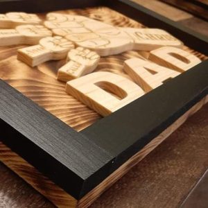 Handcrafted wooden home decor sign made by Bergeron Woodgrains. Black painted frame with natural wood name label such as Dad with matching big fist bump surrounded by smaller fist bumps with matching children’s names all on a flame torched wood background.