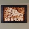 Handcrafted wooden home decor sign made by Bergeron Woodgrains. Black painted frame with natural wood name label such as Grandpa with matching big fist bump surrounded by smaller fist bumps with matching children’s names all on a flame torched wood background.