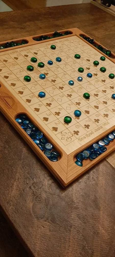 Handcrafted wood sequence board game featuring a cherry border with game piece cutouts and laser engraved baltic birch centre and walnut miter keys on each corner. Canadian made by Bergeron Bergeron