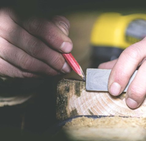 Woodworker using a speed square to mark out cutting lines on a piece of wood