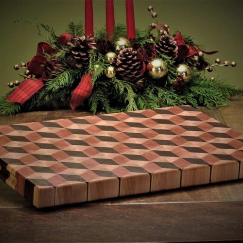 Handcrafted 12x18" 3D tumbling block end grain cutting board resting slightly elevated on a harvest table